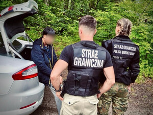 Patrol Straży Granicznej. W tle zatrzymany cudzoziemiec. Fot. MOSG Patrol Straży Granicznej. W tle zatrzymany cudzoziemiec. Fot. MOSG