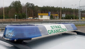 Fot. MOSG Dach samochodu z belką z napisem &quot;Straż Graniczna&quot;, w tle widoczny znak drogowy &quot;Granica państwa&quot;.