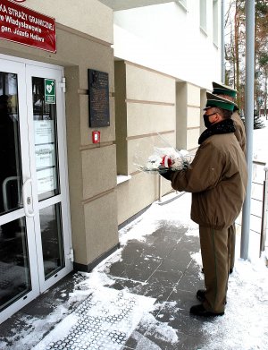  Funkcjonariusze PSG we Władysławowie składają kwiaty pod tablicą patrona.