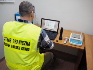 Fot. MOSG Funkcjonariusz SG z pomocą urządzeń analizuje dokument.