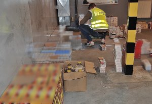 Fot. MOSG W pomieszczeniu jest funkcjonariusz SG, wokół niego zatrzymane paczki z papierosami i alkohol.