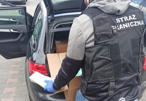 Fot. MOSG Funkcjonariusz Straży Granicznej wypakowuje przemycone papierosy.
