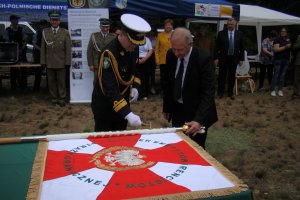 Fot. ZEiRSG w Szczecinie Kontradmirał SG Andrzej Prokopski wbija gwóźdź w drzewiec sztandaru dla Związku Emerytów i Rencistów Straży Granicznej w Szczecinie