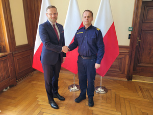 Fot. ZUW Komendant MOSG i wojewoda zachodniopomorski ściskają sobie dłonie na tle flag RP.