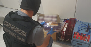 Fot. MOSG Funkcjonariusz SG klęczy przy ujawnionych papierosach.