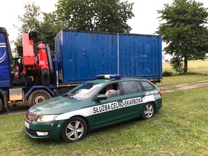 Fot. KAS Samochód służby celno-skarbowej, w tle kontener z krajanką tytoniową.