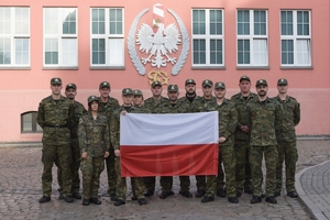 Fot. OSSSG Funkcjonariusze stoją z polską flagą.