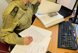 Fot. MOSG Funkcjonariuszka Straży Granicznej pochylona nad dokumentami.