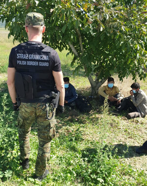 Funkcjonariusz SG podczas patrolu w Macedonii, w tle zatrzymani migranci. Funkcjonariusz SG podczas patrolu w Macedonii, w tle zatrzymani migranci.