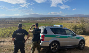 Funkcjonariusz SG i macedoński policjant podczas patrolu. Funkcjonariusz SG podczas patrolu w Macedonii, w tle zatrzymani migranci.