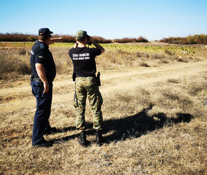 Funkcjonariusz SG i macedoński policjant podczas patrolu. Funkcjonariusz SG podczas patrolu w Macedonii, w tle zatrzymani migranci.
