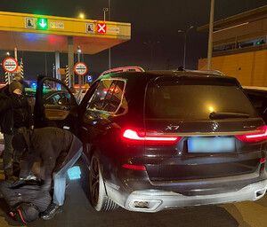 Funkcjonariusze Straży Granicznej zatrzymują kierowcę kradzionego BMW. Funkcjonariusz Straży Granicznej przy zatrzymanym BMW.