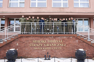 Wspólne zdjęcie uczniów z funkcjonariuszem MOSG przed wejściem do budynku Komendy MOSG Wspólne zdjęcie uczniów z funkcjonariuszem MOSG przed wejściem do budynku Komendy MOSG