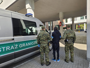 Funkcjonariusze doprowadzają do pojazdu służbowego zatrzymanego obywatela Gruzji. Fot. MOSG Funkcjonariusze doprowadzają do pojazdu służbowego zatrzymanego obywatela Gruzji. Fot. MOSG